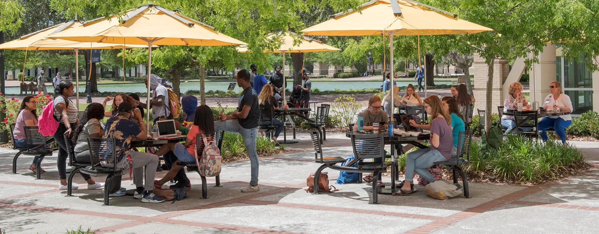 Many students at outside tables next to the CSU dining hall.